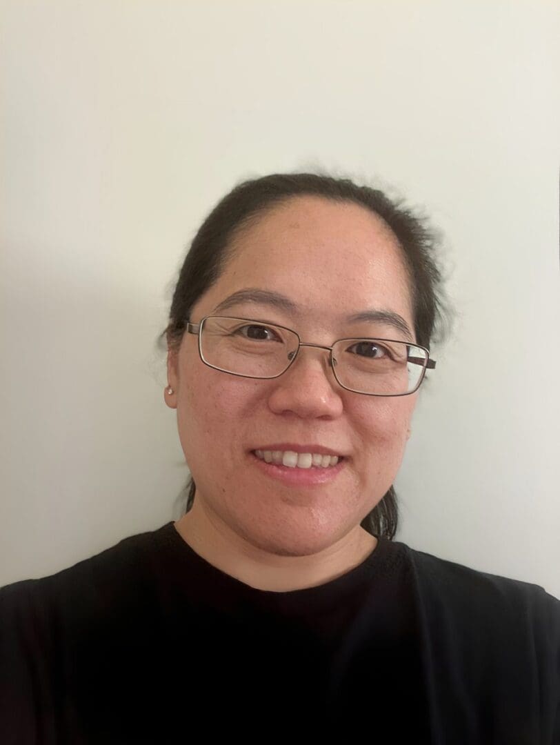 Person smiling with glasses and black shirt.