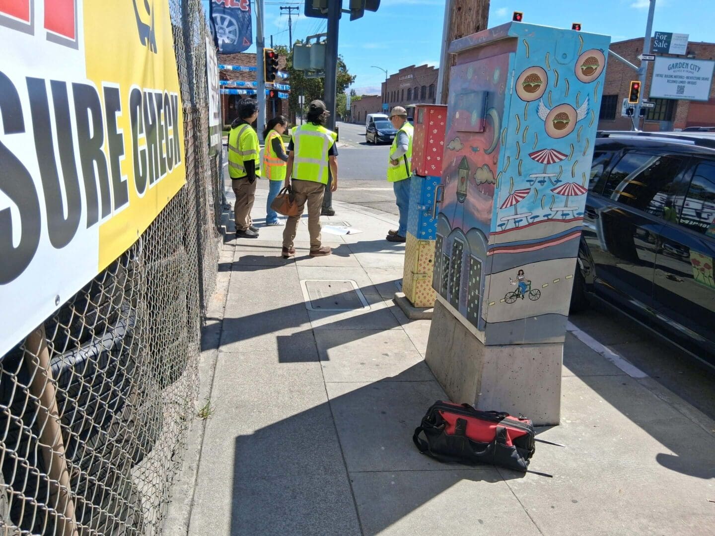 Workers in safety vests on urban sidewalk.
