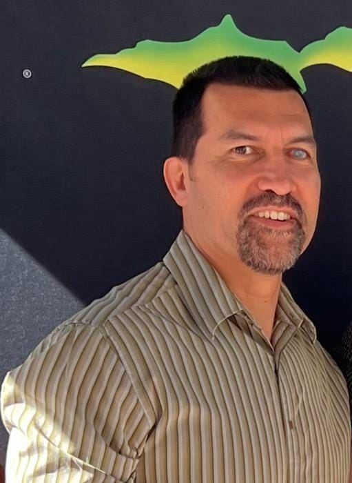 Man smiling in front of abstract background.