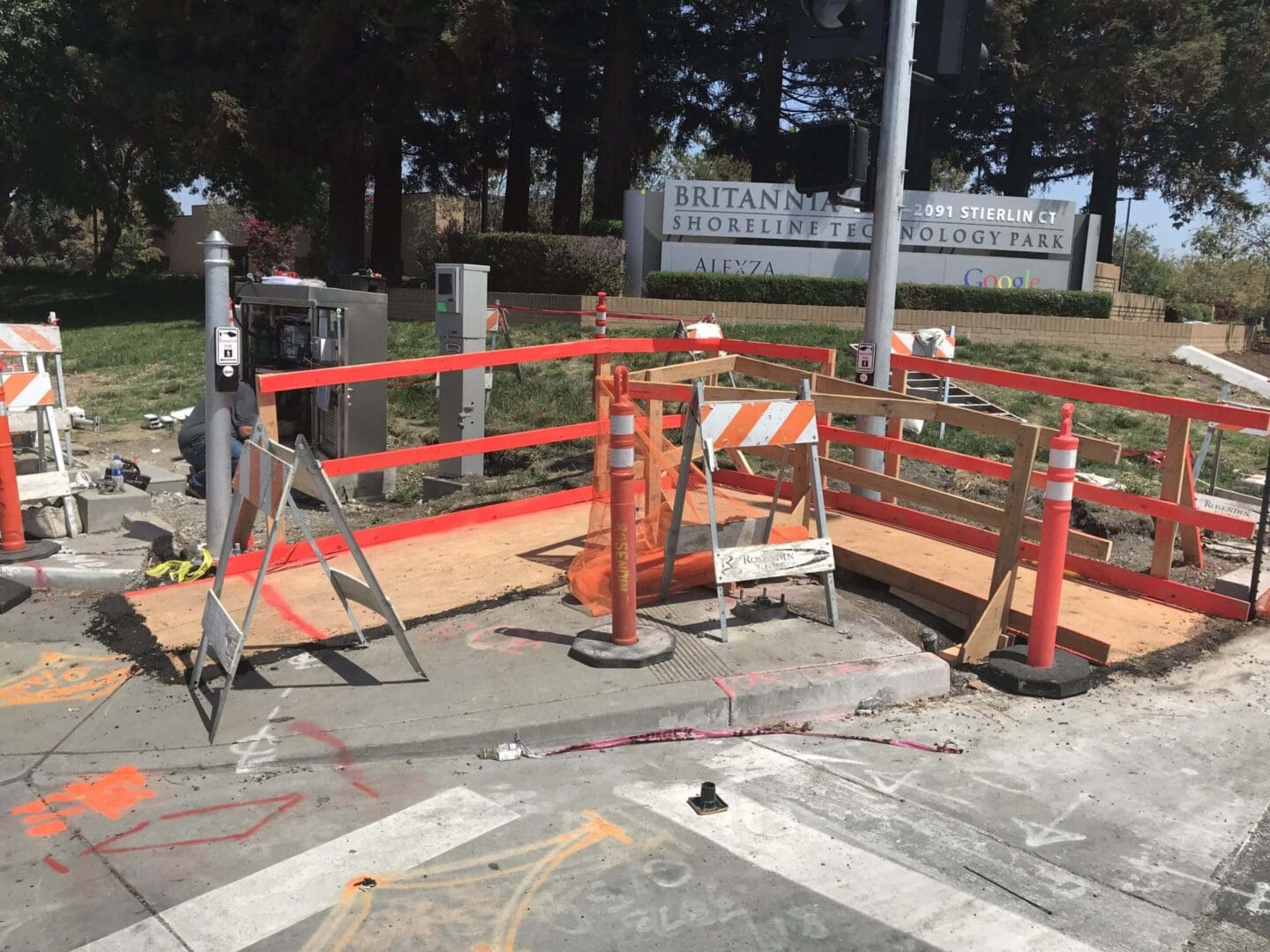Sidewalk construction site with caution barriers.