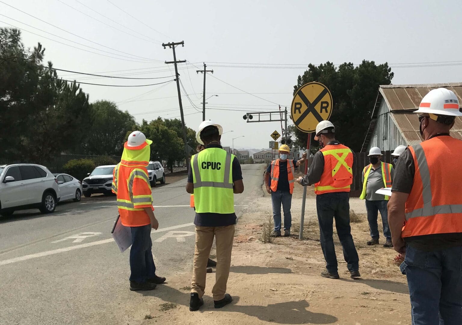 Workers inspecting railroad crossing near road.